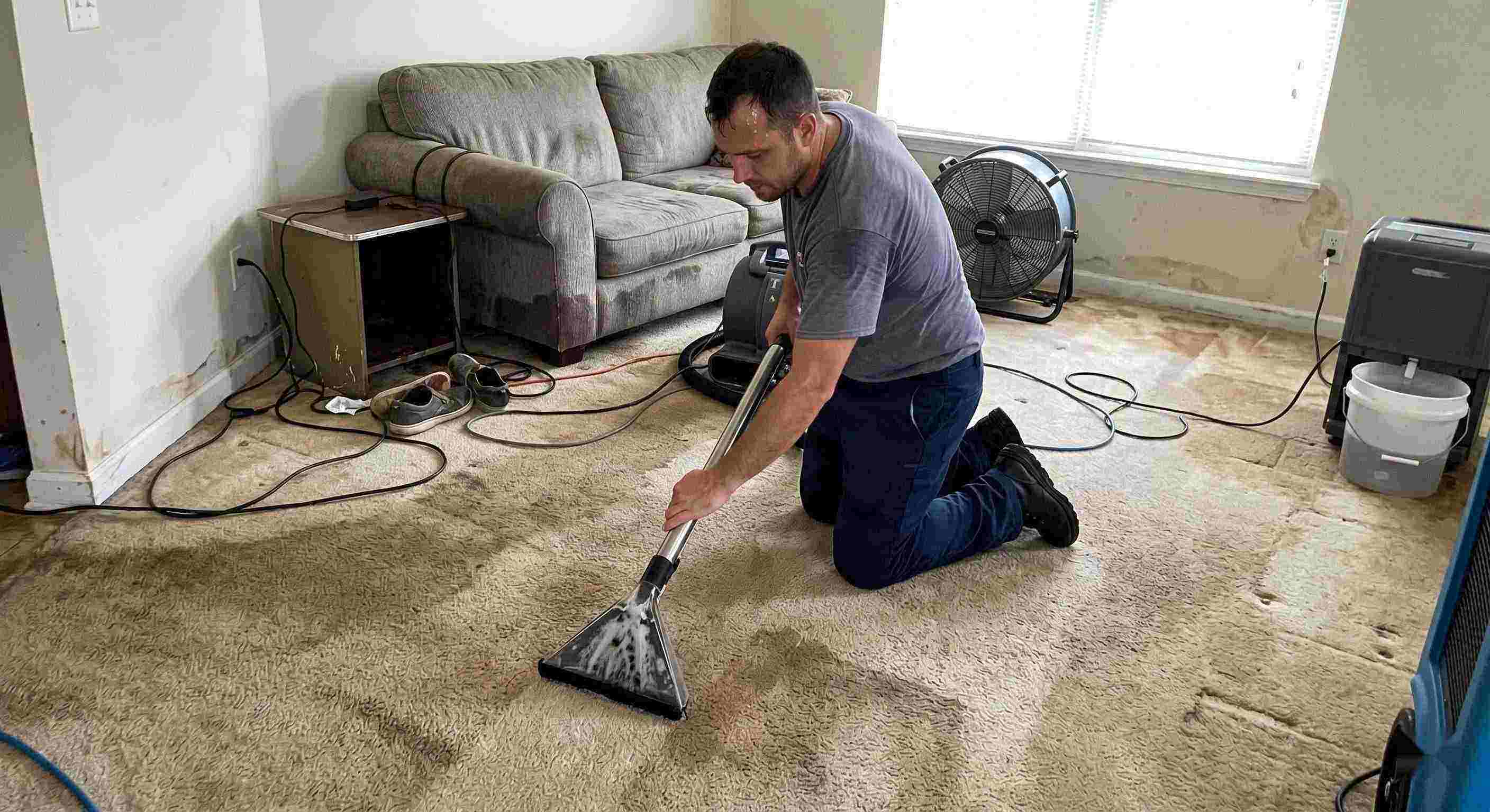 Technician performing carpet water extraction in a residential home using professional equipment after water damage in Chesapeake