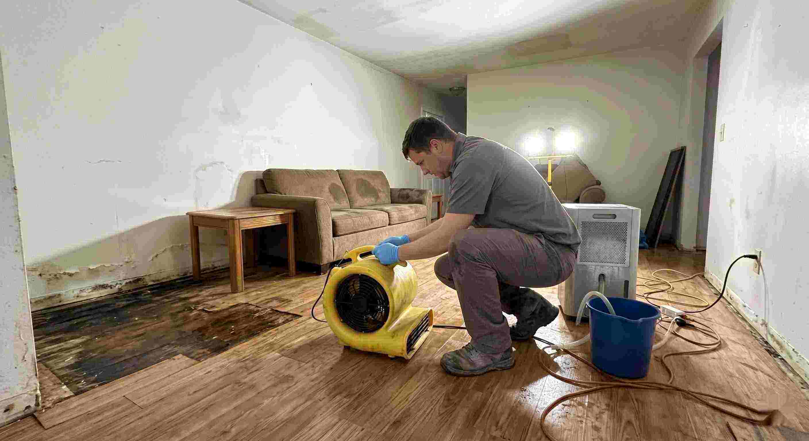Expert water damage restoration technician drying wet floors with equipment during cleanup process in Frederick